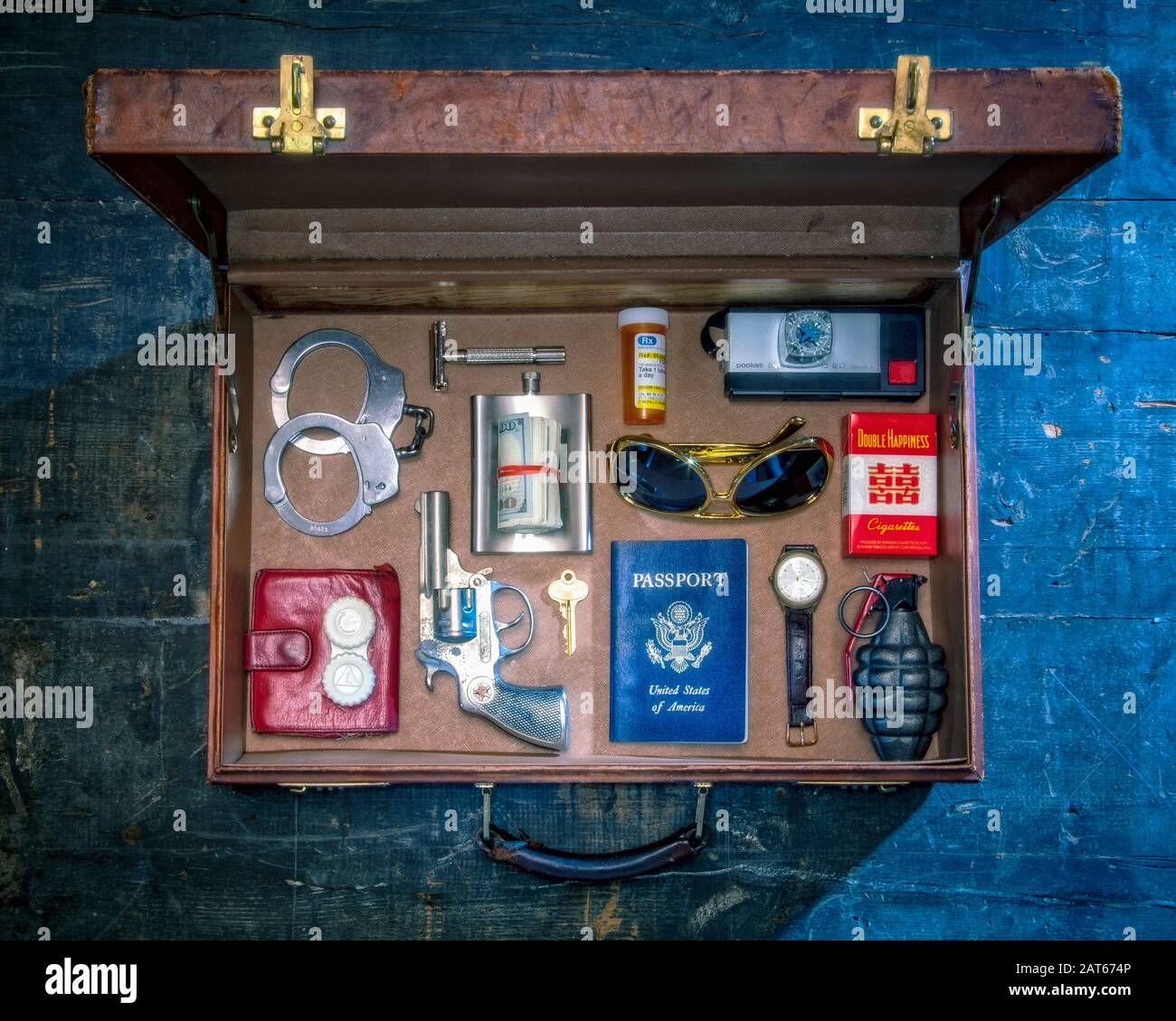 Una vista dall'alto di una valigetta in pelle di vecchio stile con oggetti da viaggio pericolosi accuratamente disposti all'interno in modo ordinato Foto Stock