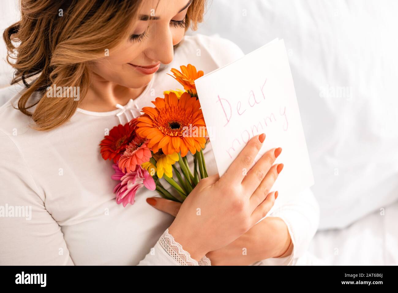 felice donna sorridente tenendo bouquet di gerberi e mamme carta da giorno Foto Stock
