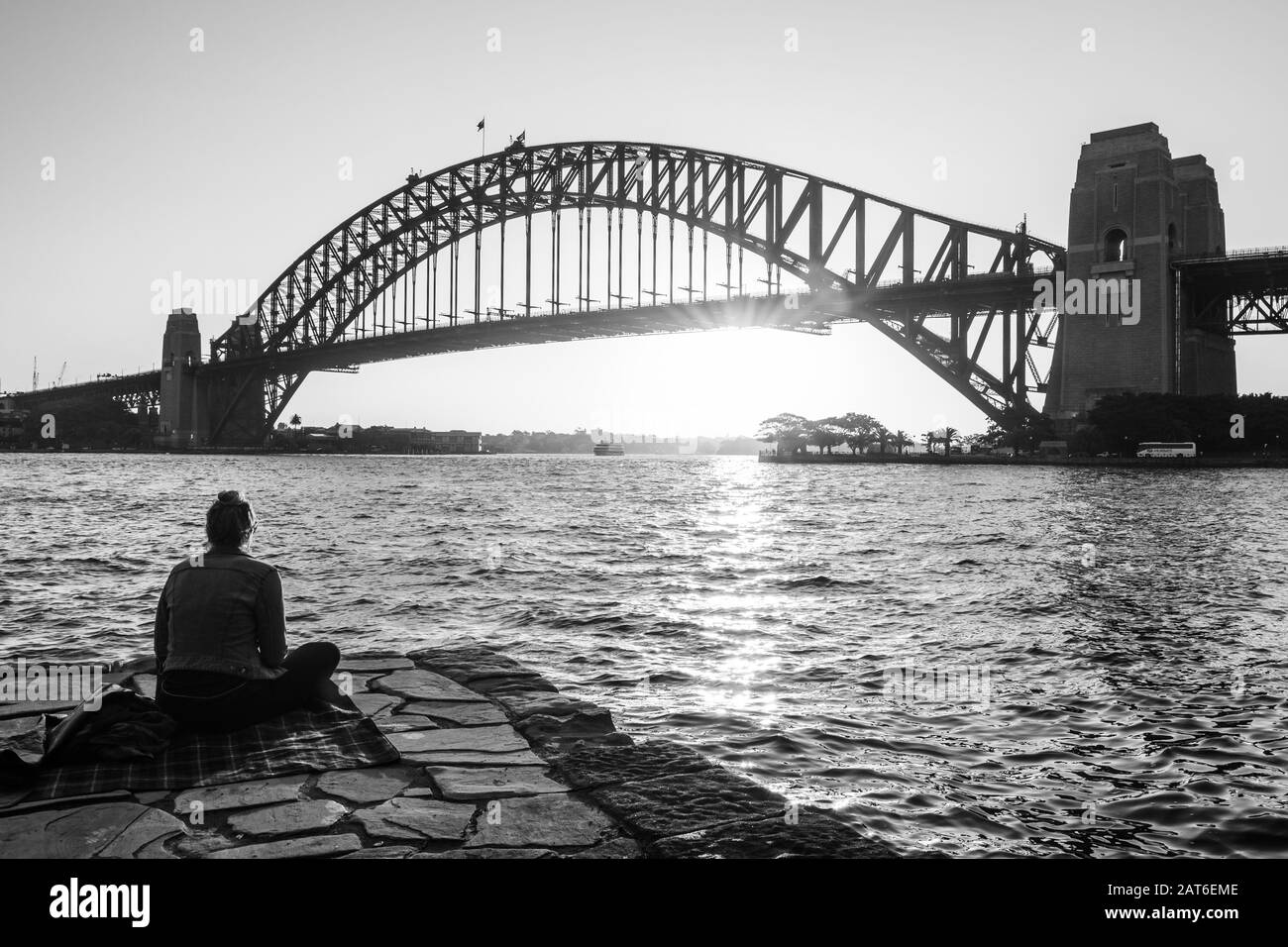 Lady contemplando il tramonto dietro il ponte del porto Foto Stock