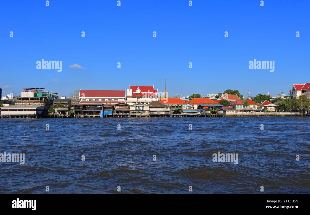 Il paesaggio urbano di Bangkok mostra le case e gli edifici in stile thailandese sul lungomare lungo il fiume Chao Phraya, vista dalla barca turistica Foto Stock