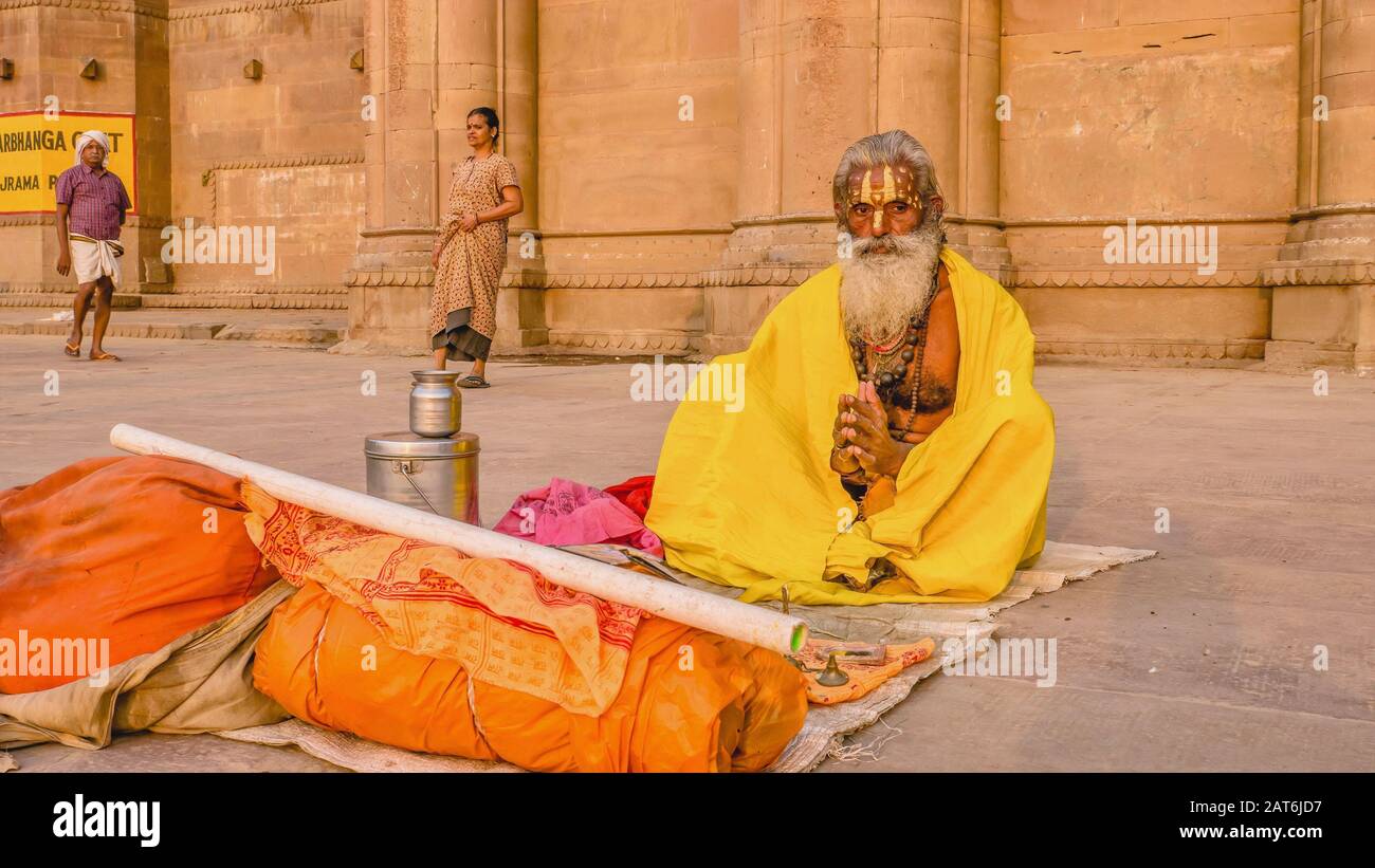 Varanasi, India - 12 Novembre 2015. Un sadhu indù siede con i suoi pochi beni mondani su un tappeto su Darbhanga Ghat. Foto Stock
