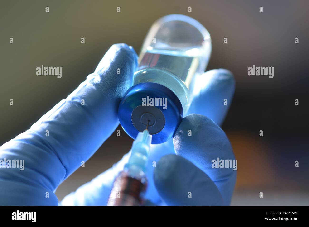 La siringa aspira il farmaco liquido dal flaconcino di colore blu nella mano gloved dell'infermiere. Foto Stock