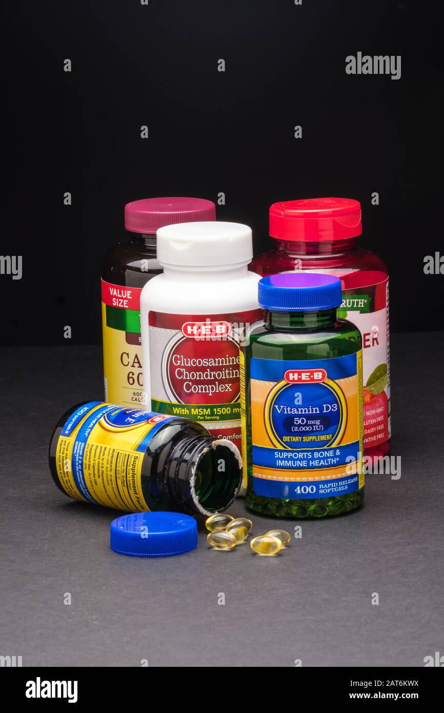 Integratori vitaminici assortiti nelle loro bottiglie su sfondo scuro Foto Stock