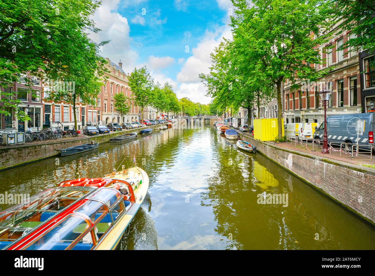 Una barca turistica viaggi un pittoresco canale di Amsterdam su un pomeriggio nella tarda estate Foto Stock