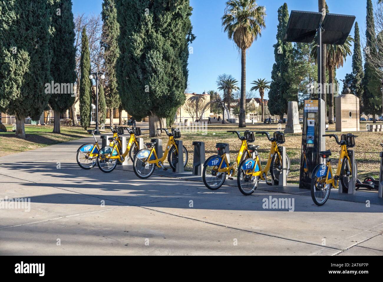 Noleggio bici Tugo con logo dello sponsor principale Tucson Electric Power sul perimetro di Armory Park Tucson vicino all'ingresso di un viale di alberi di Yew Foto Stock