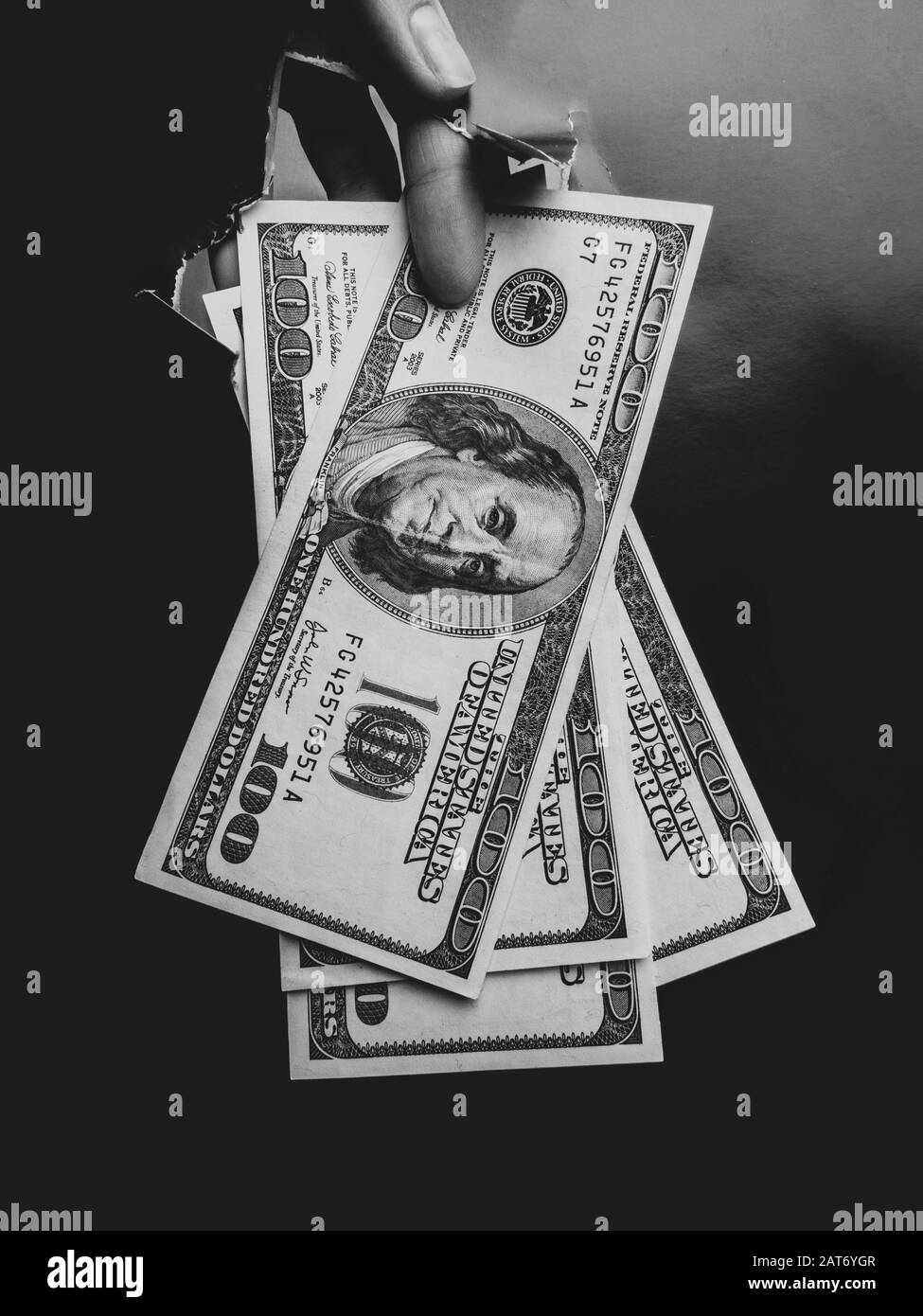 la mano appare nel foro della carta nera strappata. Il concetto di donazione, profitto, corruzione, povertà, benefici, borse di studio e generosità. Foto Stock