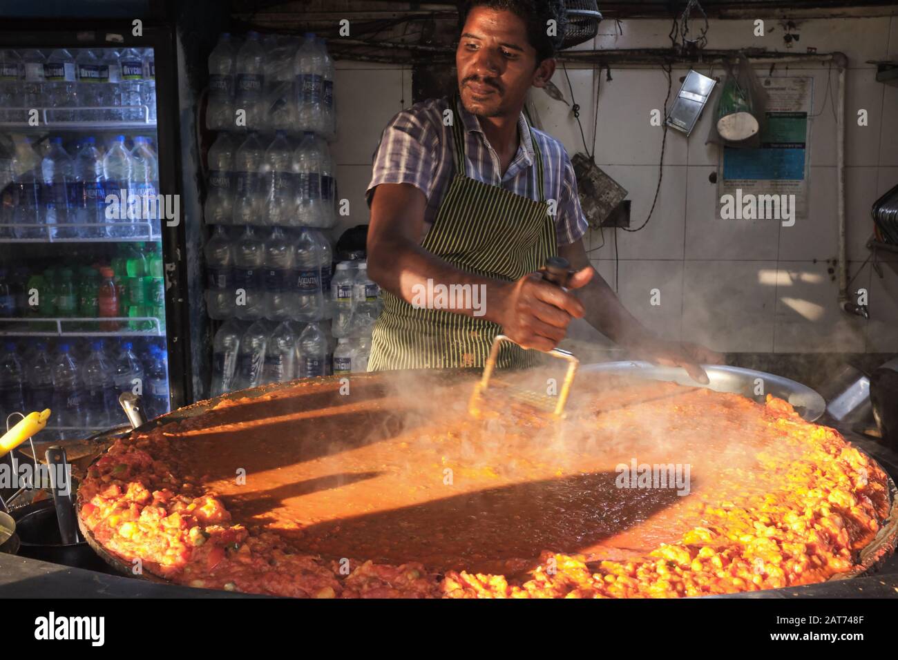 Un cuoco ad una stalla di cibo a Mumbai, India, fa 'bhaji', una mescolanza di verdure e parte del cibo indiano poco costoso e popolare o dell'alimento di strada Pad Bhaji Foto Stock