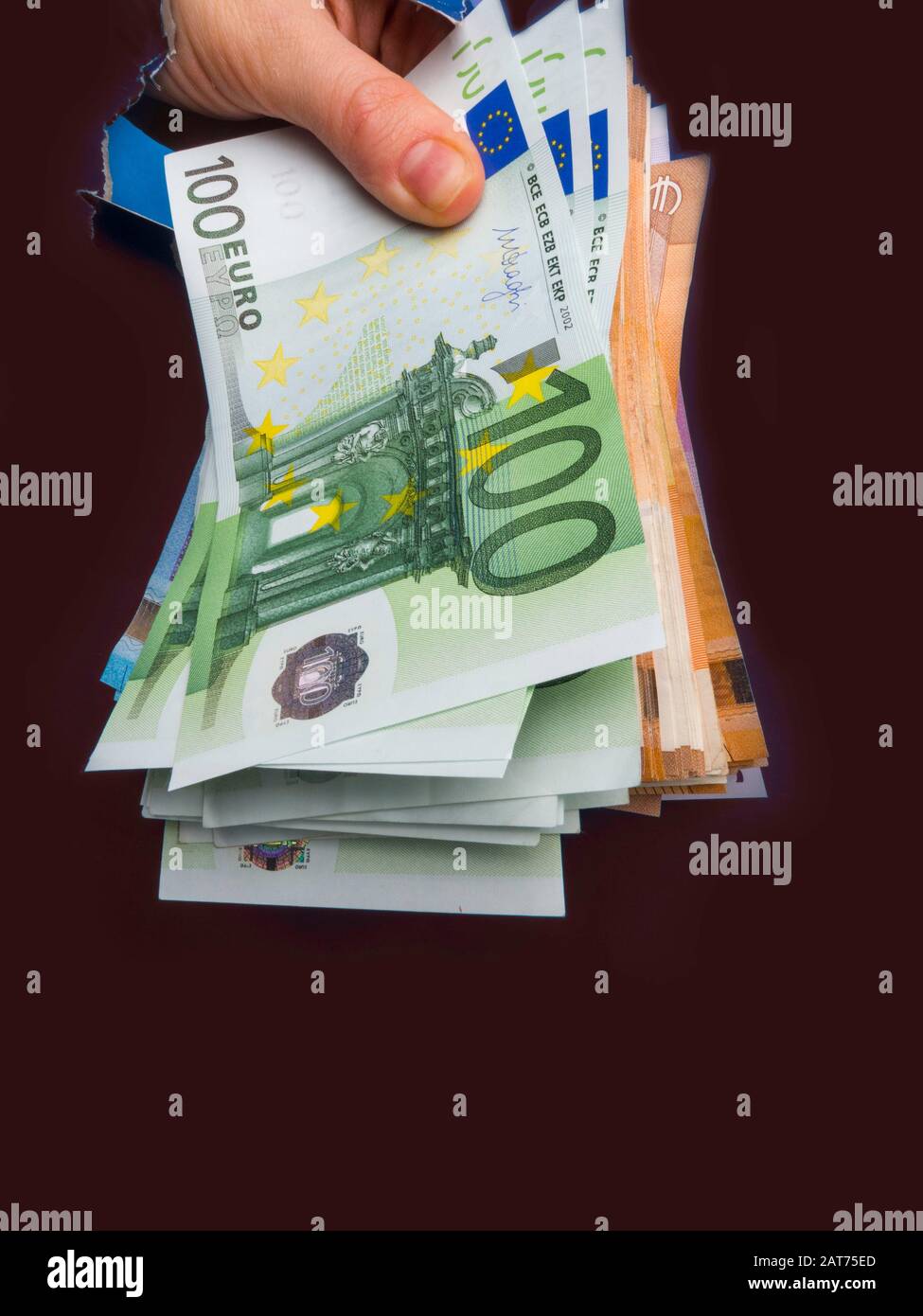 mano appare euro valuta all'interno buco da carta strappata, il concetto di dono in contanti, sorpresa, vittoria, tasse di trattamento, tangenti, chirurgia illegale. Foto Stock