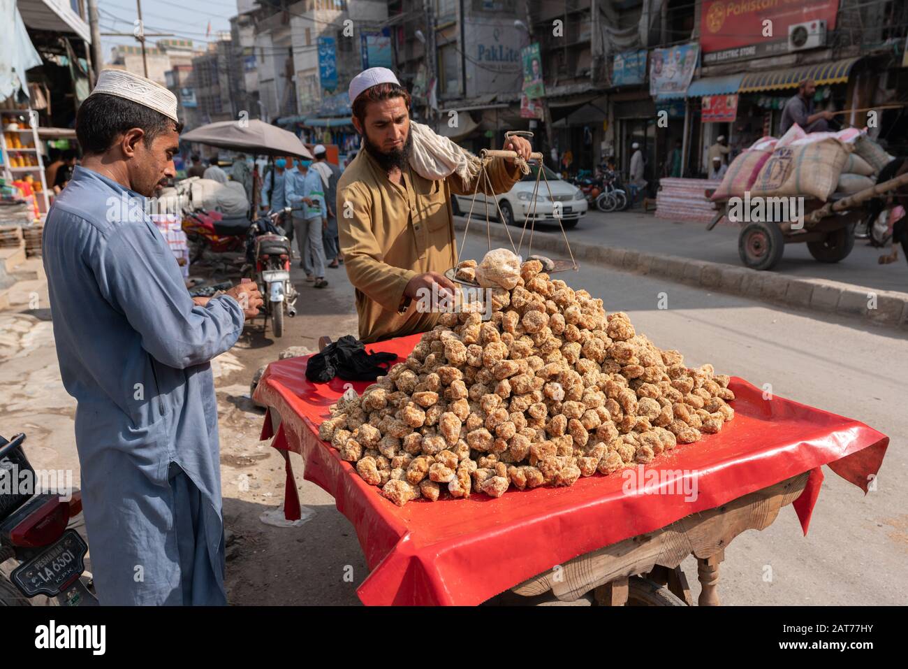 Pashtun uomo che vende jaggery ('gur') da canna da zucchero per le strade di Peshawar, Pakistan Foto Stock