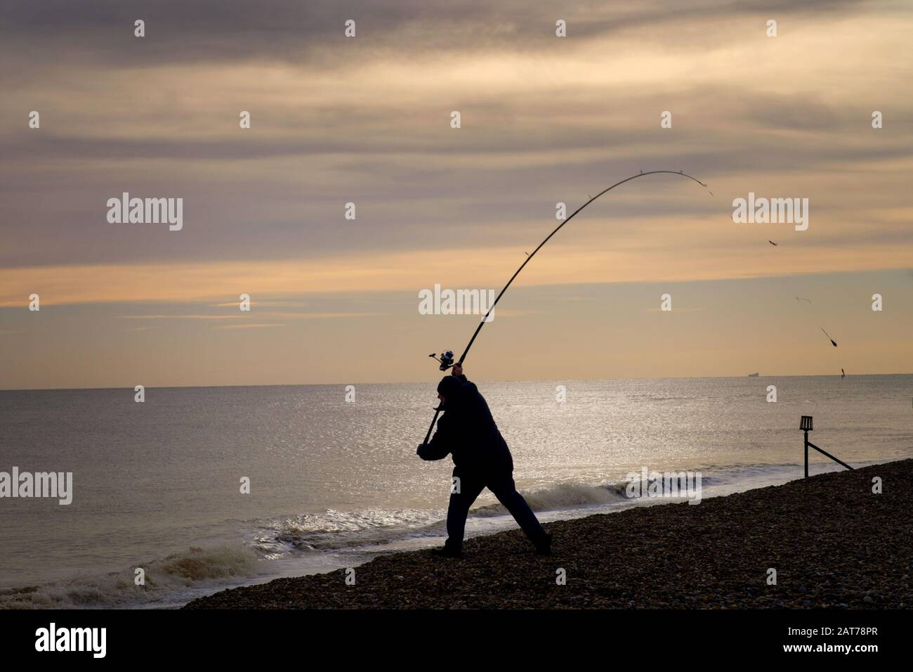 Silhouette di pesca uomo su Aldeburgh Beach, Aldeburgh, Suffolk. Foto Stock