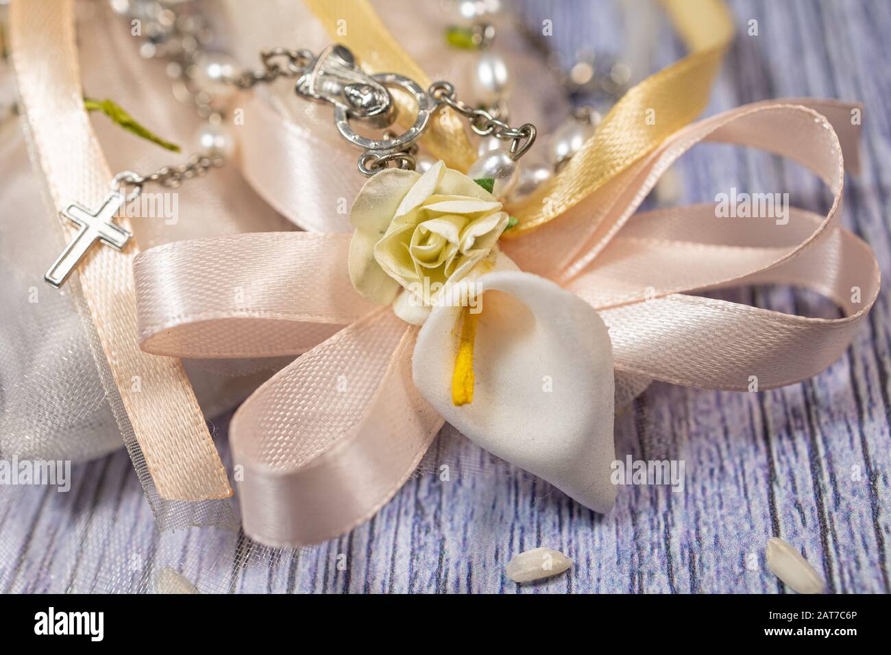 Favori di nozze. Scatole con nastro rosa e oro contenente confetti e piccolo regalo cristiano rosario. Foto Stock