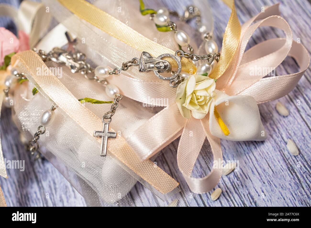 Favori di nozze. Scatole con nastro rosa e oro contenente confetti e piccolo regalo cristiano rosario. Foto Stock