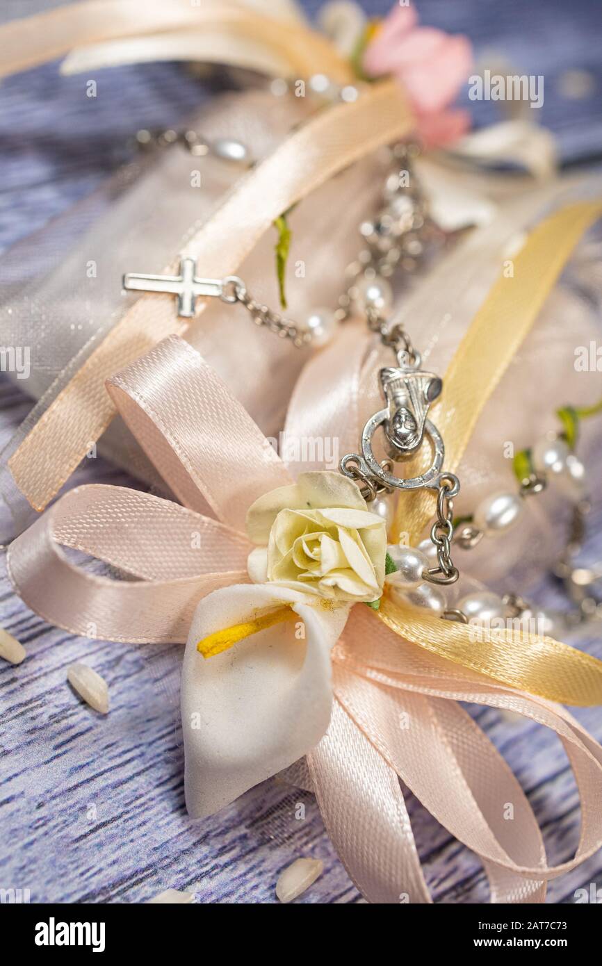 Favori di nozze. Scatole con nastro rosa e oro contenente confetti e piccolo regalo cristiano rosario. Foto Stock