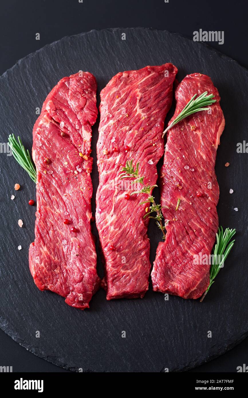 Concetto di cibo biologico carne cruda filetto bistecca di manzo su sfondo di ardesia nera pietra Foto Stock