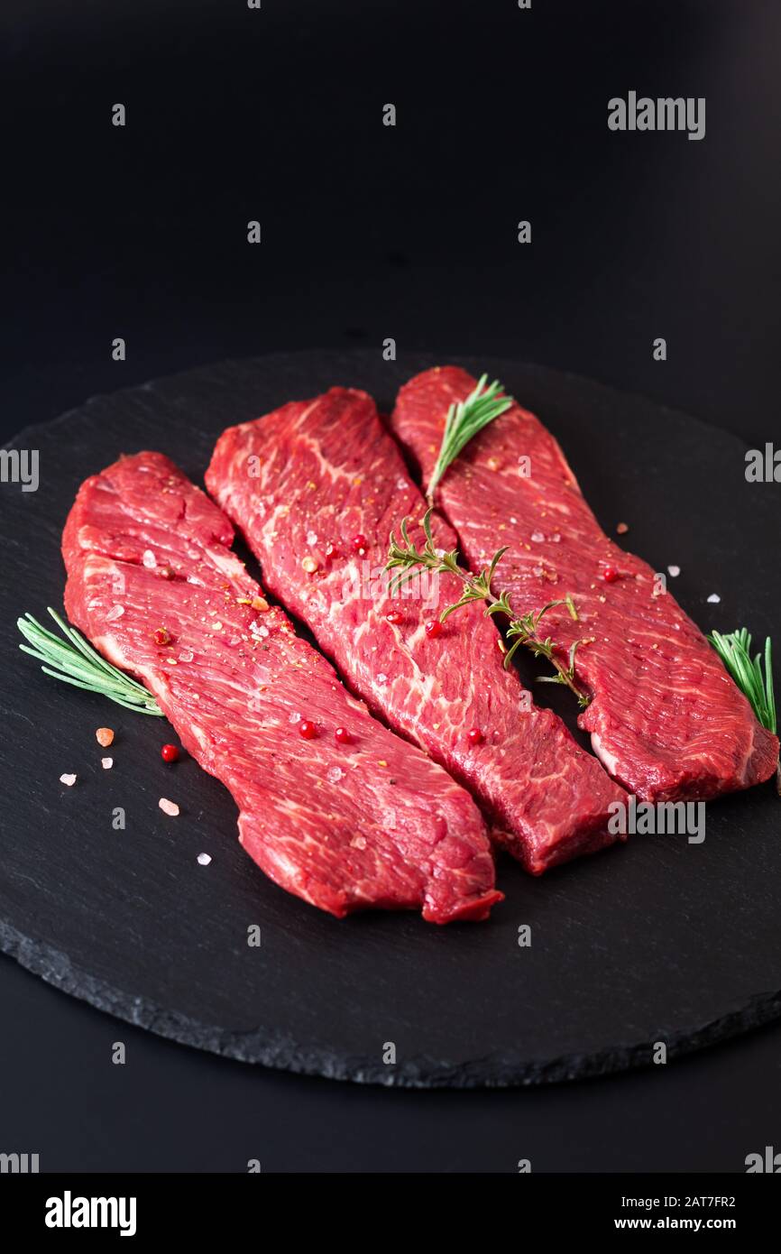 Concetto di cibo biologico carne cruda filetto bistecca di manzo su sfondo di ardesia nera pietra Foto Stock