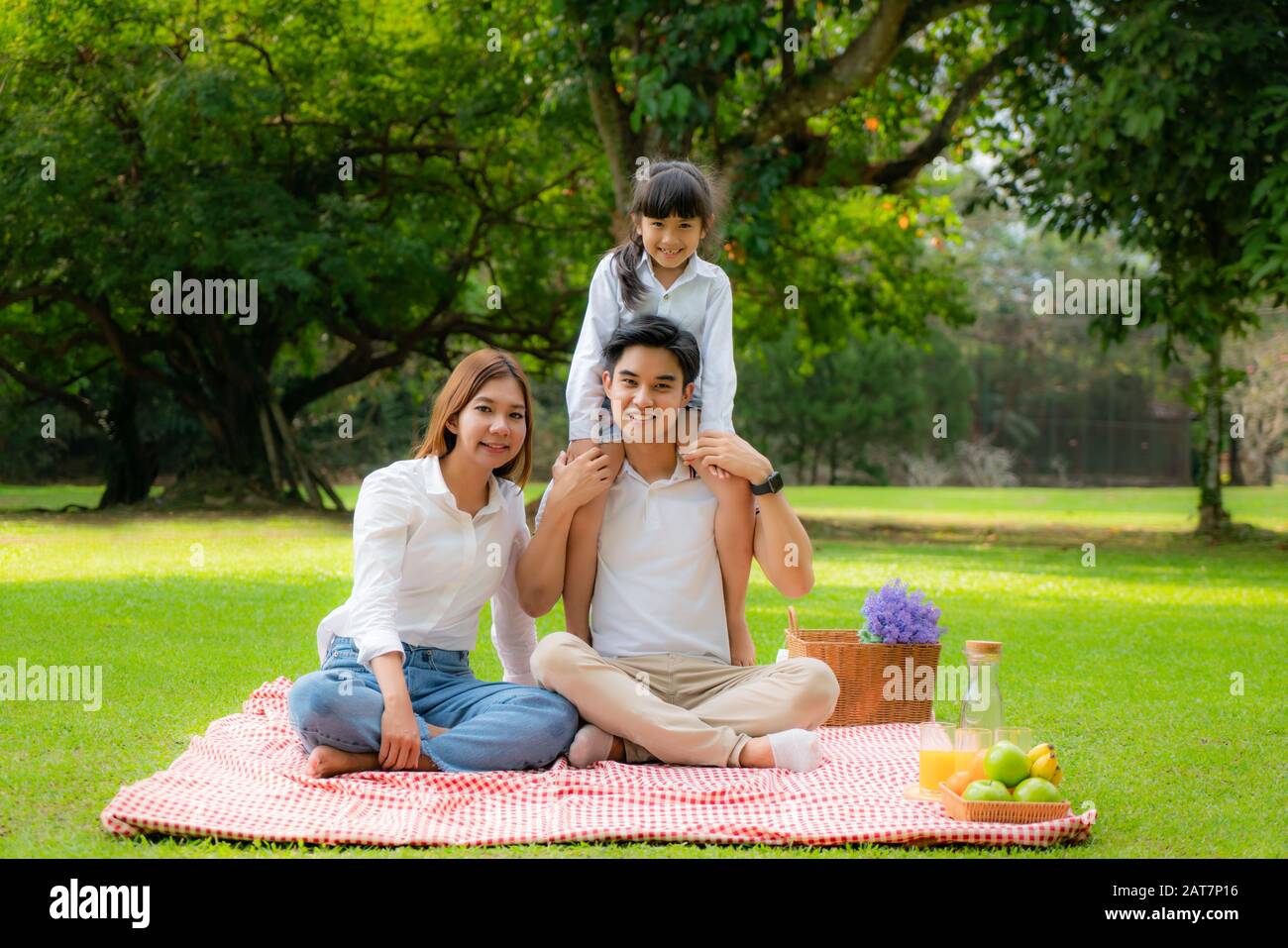 Asian teen famiglia felice vacanza pic-nic momento nel parco con padre, madre e figlia guardando la macchina fotografica e sorriso per trascorrere felice vacanza a Foto Stock