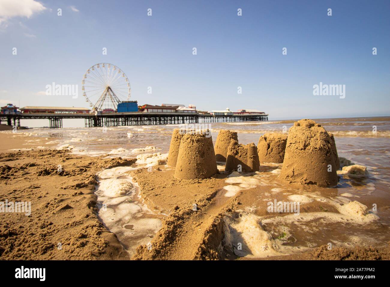 Castelli di sabbia con la fiera sul molo centrale di Blackpool sullo sfondo Foto Stock