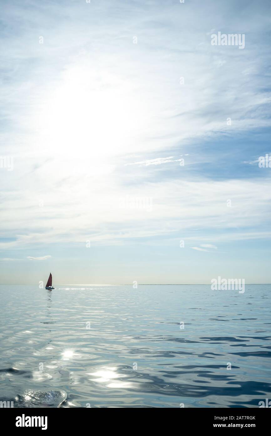 Meraviglioso paesaggio estivo. Barca a vela in mare all'orizzonte contro il cielo blu con le nuvole e il sole. Vacanze attive. Foto Stock
