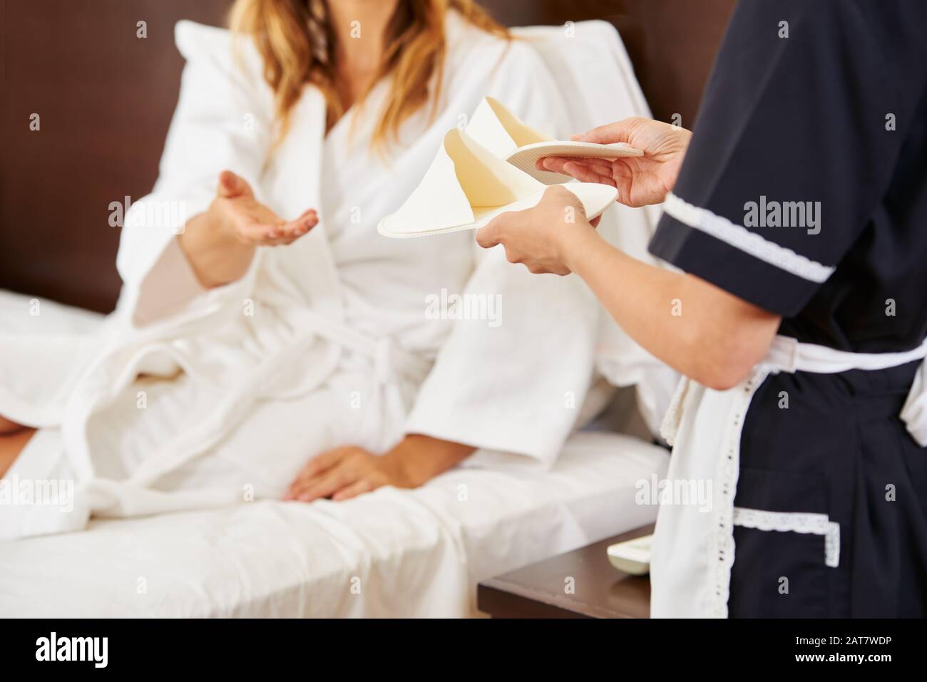 Il servizio di pulizia porta le pantofole per una donna nella camera dell'hotel Foto Stock