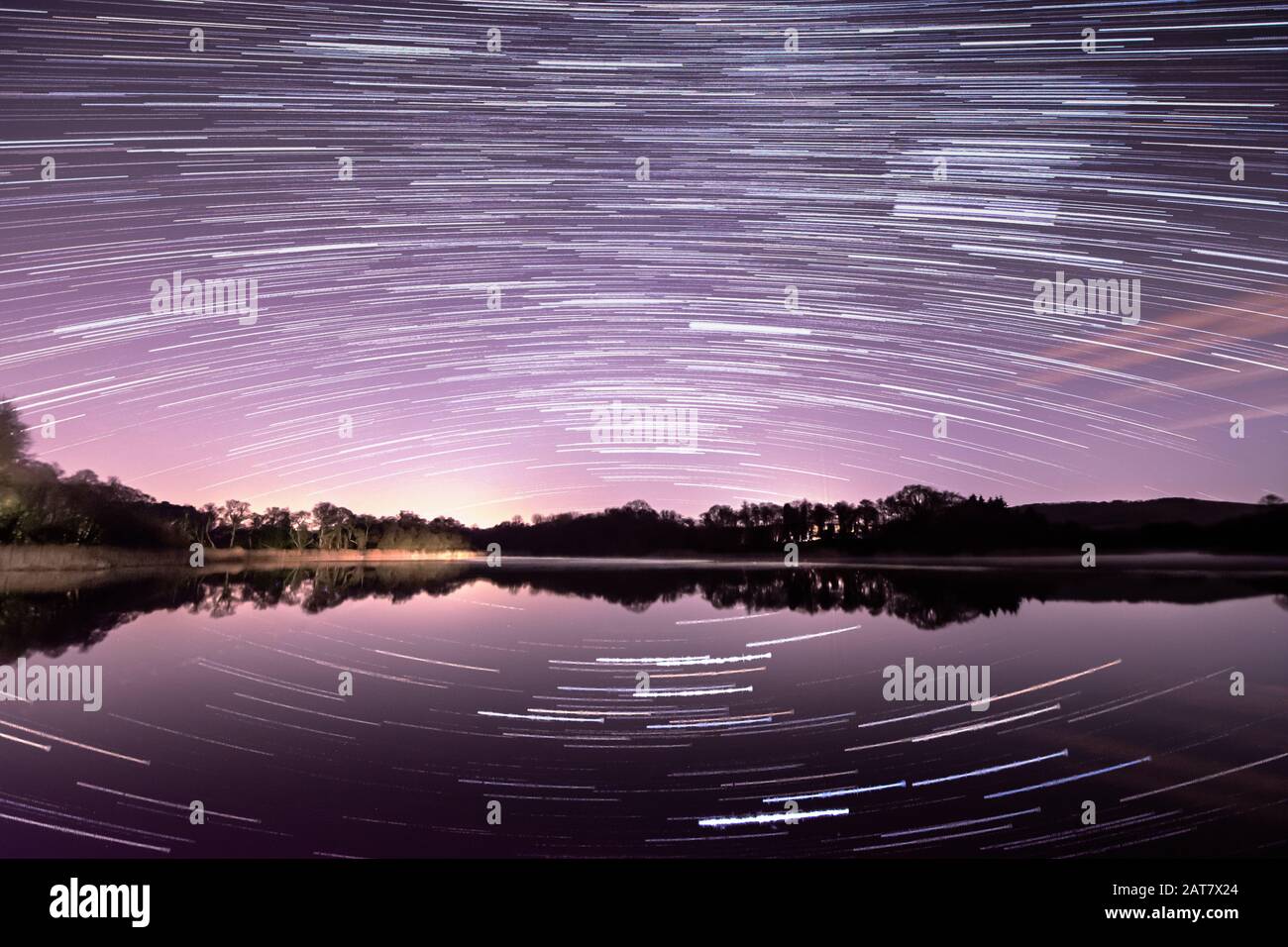 Startrail del cielo meridionale su Burton Mill Pond, West Sussex, UK. Stelle riflesse in acqua Foto Stock