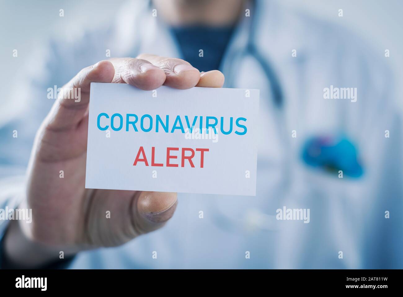 closeup di un medico caucasico che mostra un segno con il testo coronavirus avviso scritto in esso Foto Stock