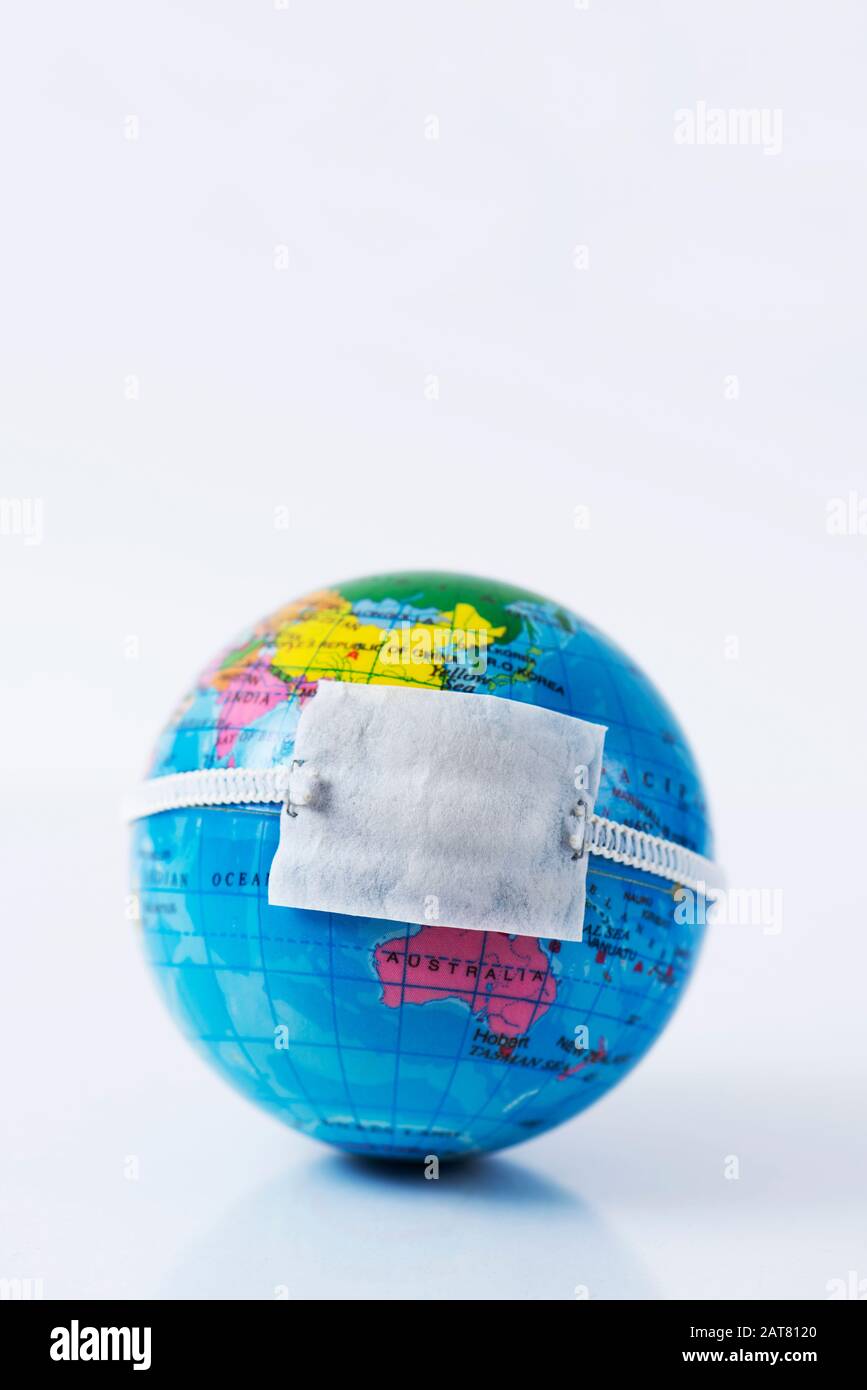 Primo piano di un globo terrestre con una maschera protettiva posta sopra la Cina, raffigurante la recente epidemia di coronavirus, con uno spazio vuoto in cima Foto Stock