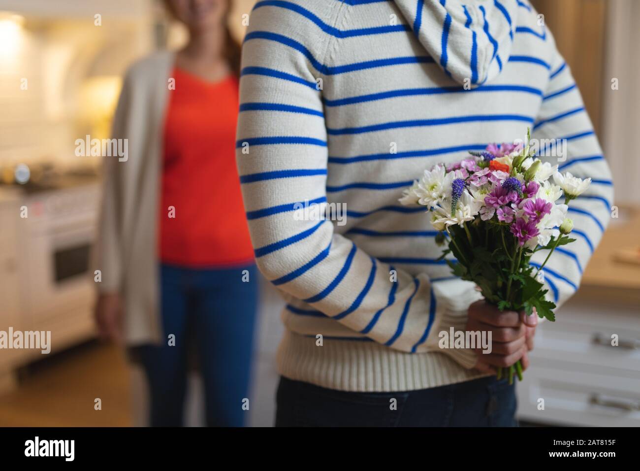 Giovane uomo che nasconde dietro la schiena un bouquet di fiori Foto Stock