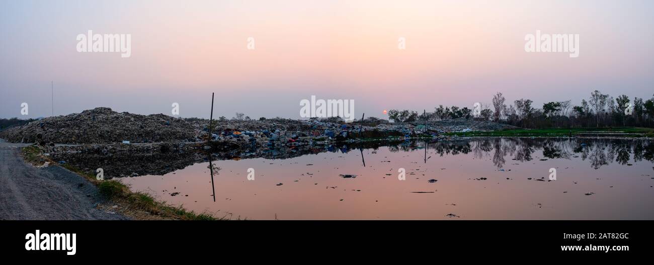 Acqua inquinata e montagna grandi mucchio di rifiuti e inquinamento al sole sta tramontando nel panorama di sfondo, pile di inchiostro e residui tossici, Questi Foto Stock