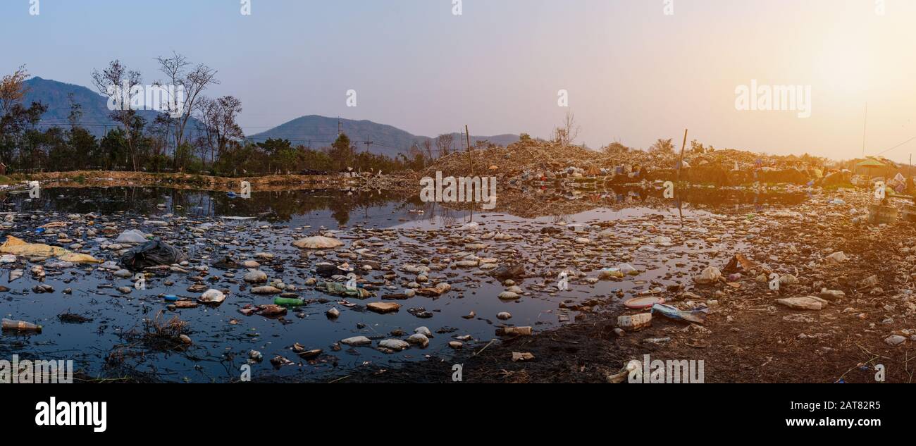 Acqua inquinata e montagna grandi mucchio di rifiuti e inquinamento al sole sta tramontando nel panorama di sfondo, pile di inchiostro e residui tossici, Questi Foto Stock