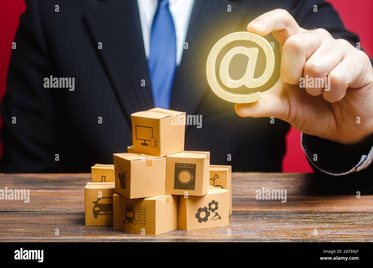 L'uomo d'affari tiene un simbolo del Internet del email sopra le scatole. Vendita prodotti di distribuzione merci online. Marketing pubblicitario. Digitalizzazione del servizio doganale Foto Stock