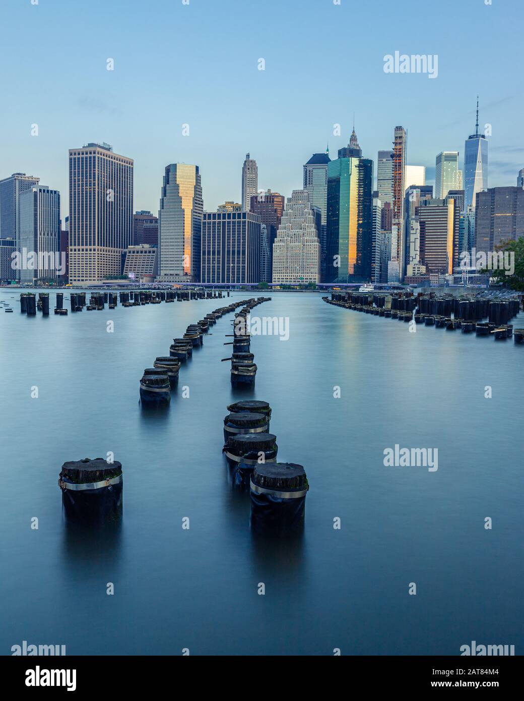 Lower Manhattan Skyline da Brooklyn Bridge Park Old Pier 1 con un arco Di Pylons Simmetrico Curva nel fiume Est durante l'alba. Foto Stock