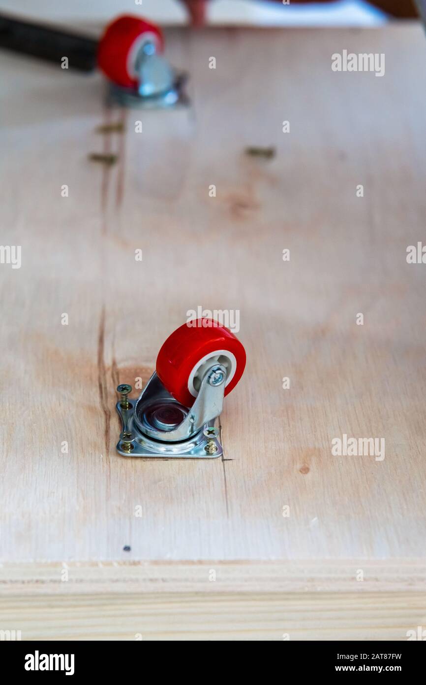 Fissaggio ruota orientabile su legno compensato, mobili. Foto Stock