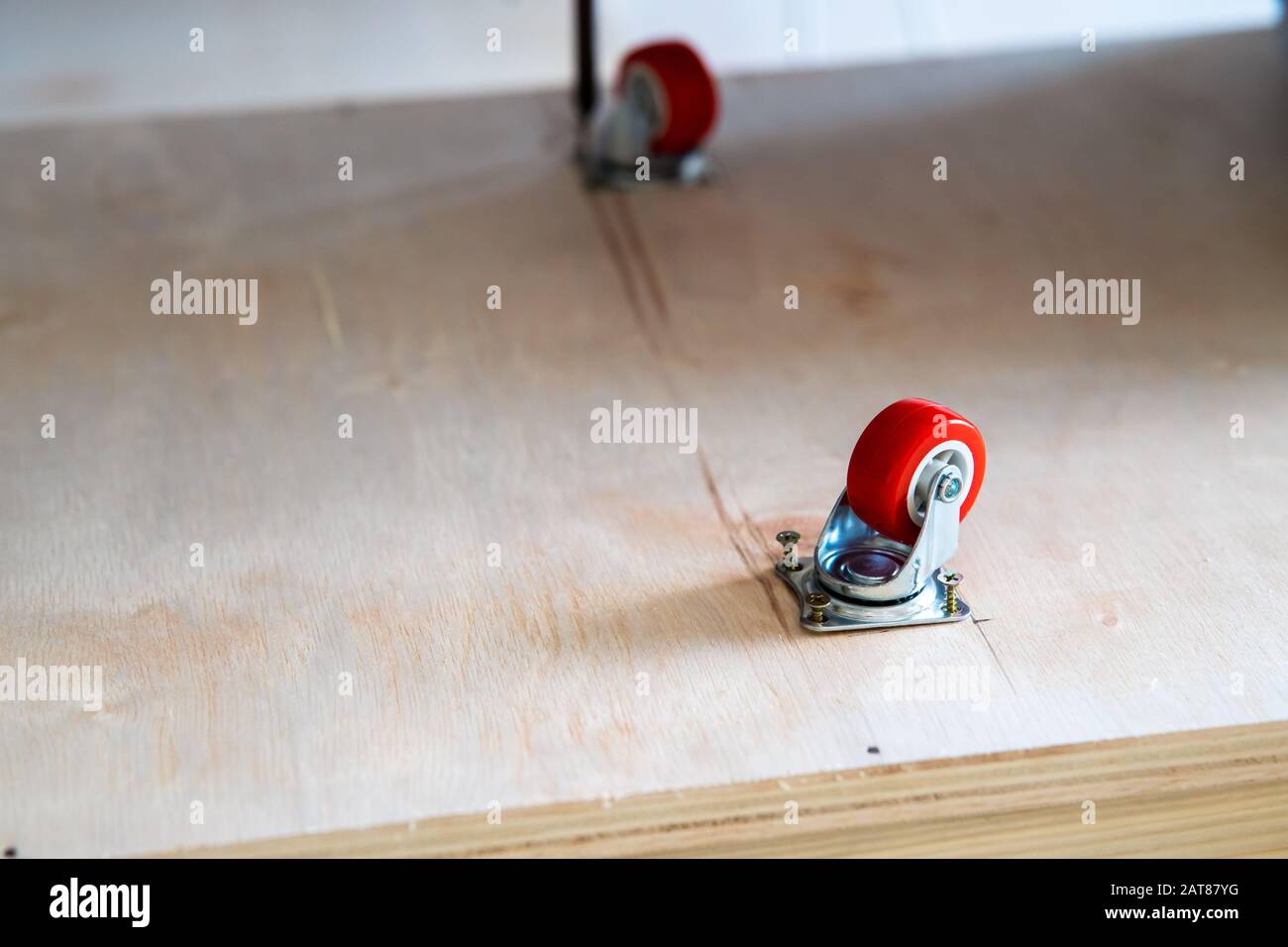 Fissaggio ruota orientabile su legno compensato, mobili. Foto Stock