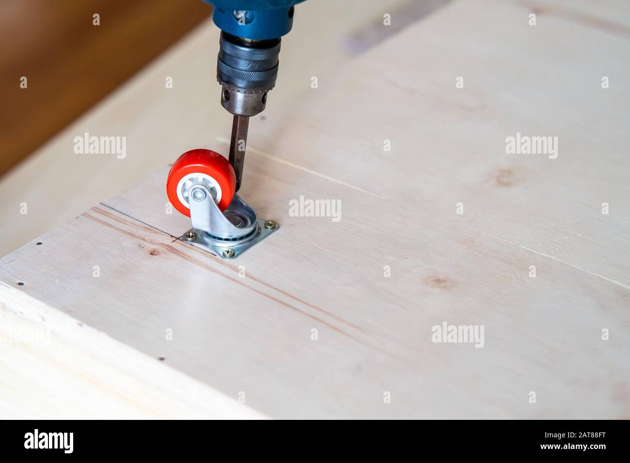 Fissaggio ruota orientabile su legno compensato, mobili. Foto Stock