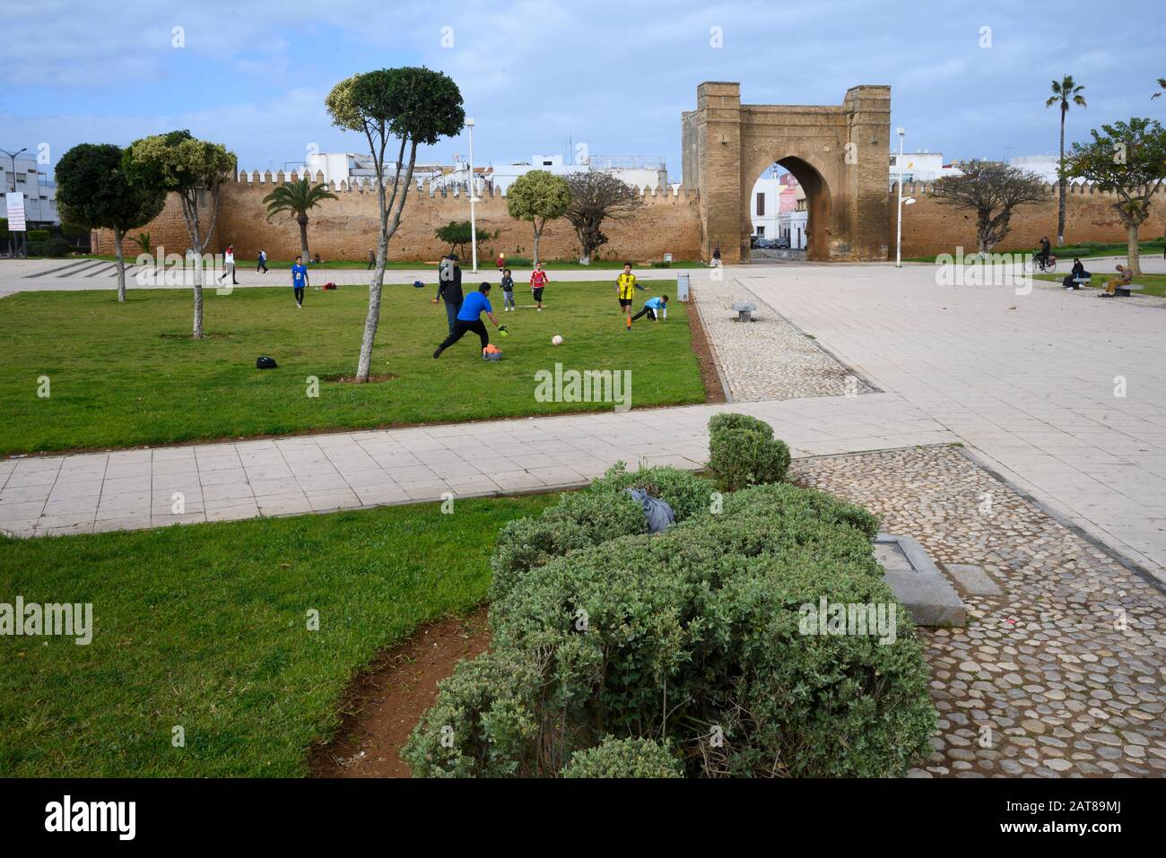 Bambini che giocano a calcio di fronte alle mura della città di Salé, Marocco Foto Stock