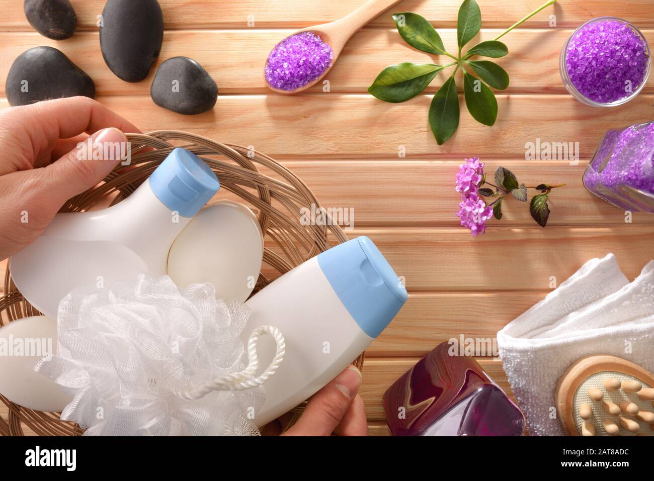 Mani che mostrano prodotti per l'igiene del bagno e altri prodotti per massaggi su tavolo in legno. Vista dall'alto. Composizione orizzontale. Foto Stock
