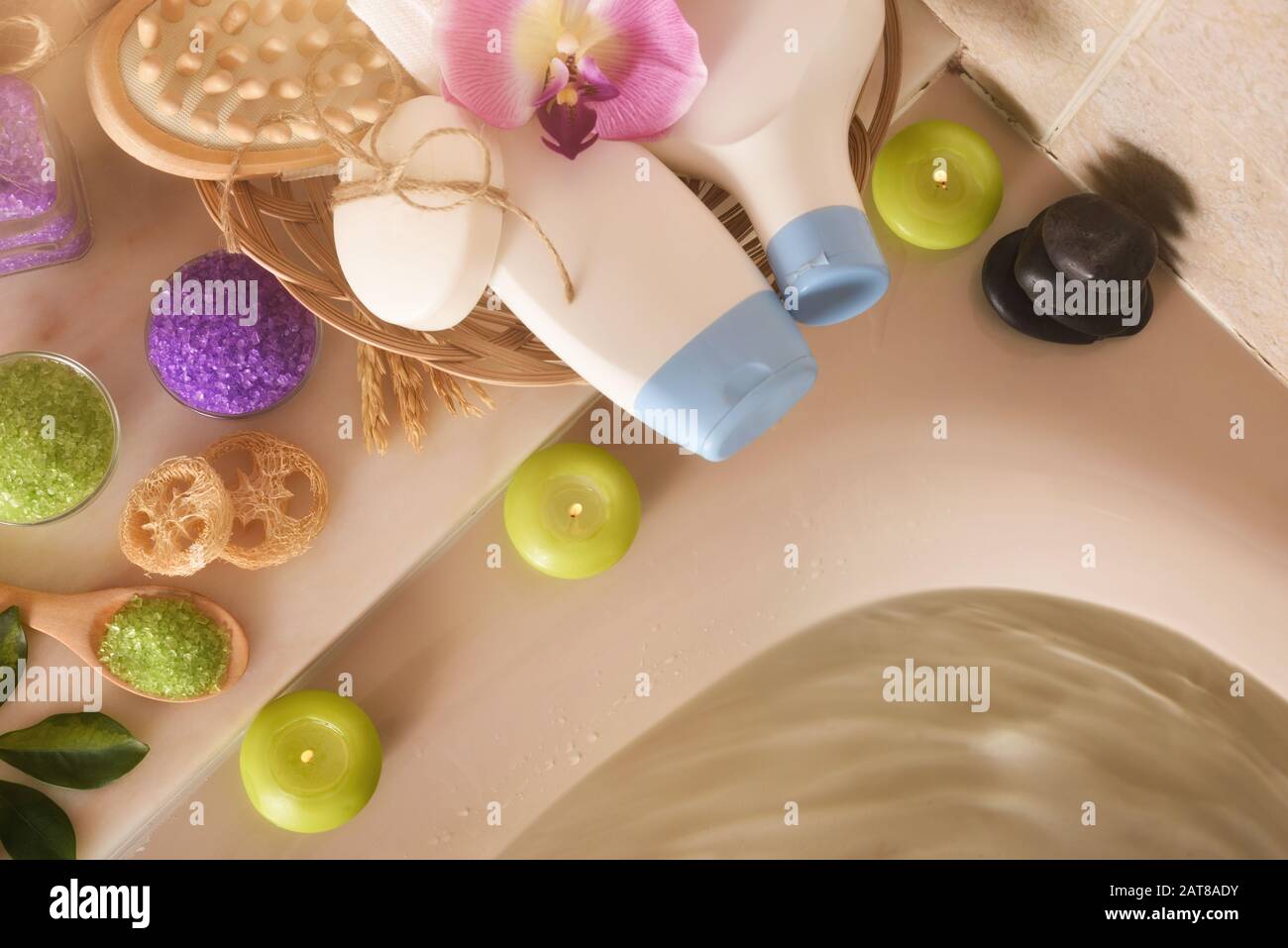 Prodotti per la cura della pelle in bagno. Gel, shampoo e sali e attrezzi da bagno nel cesto accanto a una vasca idromassaggio piena d'acqua. Vista dall'alto. Composizione orizzontale Foto Stock