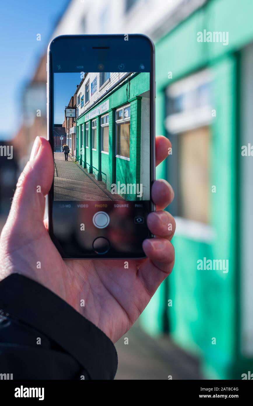 Vista ravvicinata di una mano che scatta una fotografia su un iphone/smartphone Apple Foto Stock