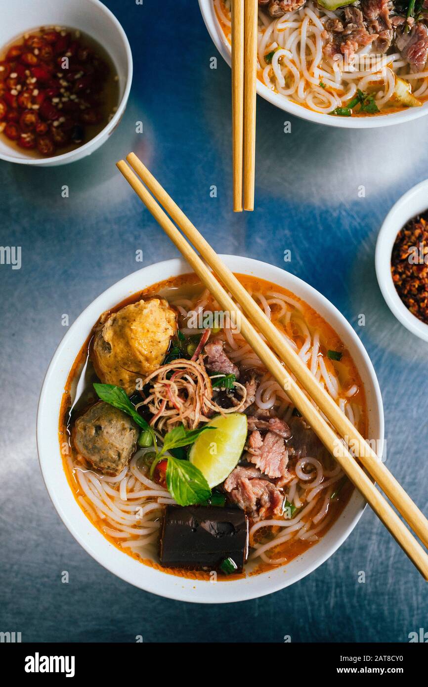 Angolo alto vicino alla ciotola di Bun Bo Hue con manzo, granchio palle, salsiccia di sangue ed erbe. Foto Stock
