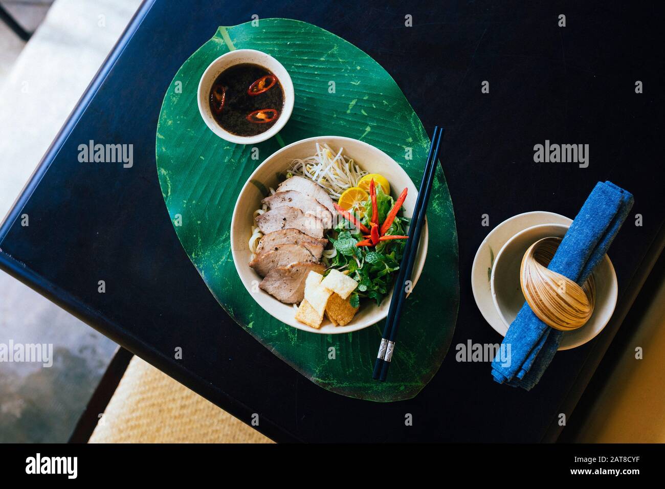 Angolo alto primo piano di ciotola di Cao Lau noodles con carne di maiale alla griglia ed erbe. Foto Stock