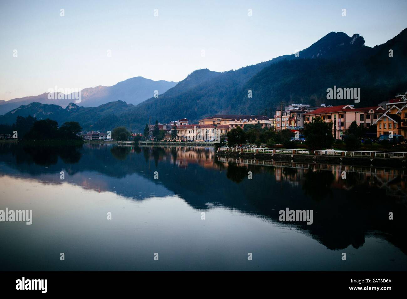 Edifici e montagne si riflettono in un piccolo lago. Foto Stock
