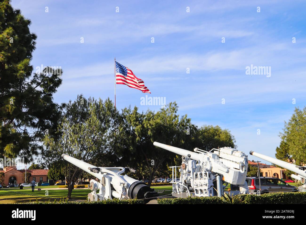 San Diego CA 1-30-2020 Grande bandiera americana che vola accanto a vecchie ex Navy calibro 50 armi in mostra al Liberty Station Park di San Diego Foto Stock