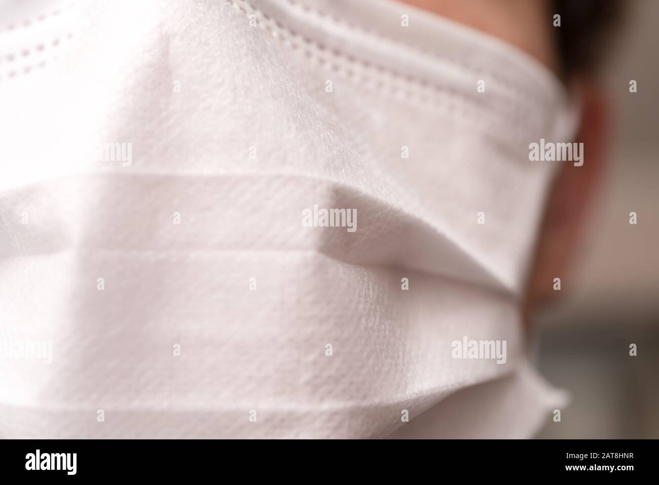 Vestirsi con il viso di un giovane che indossa una maschera medica o chirurgica Foto Stock