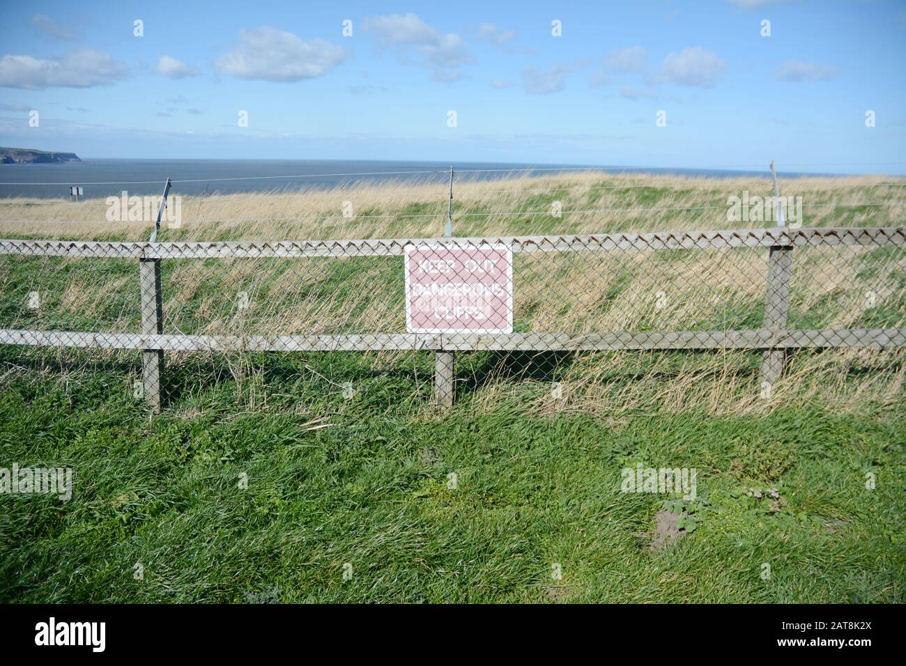 Un segnale di pericolo che avverte di una scogliera, lungo la Cleveland Way, un sentiero escursionistico nel North York Moors National Park, Yorkshire, Inghilterra, Regno Unito. Foto Stock