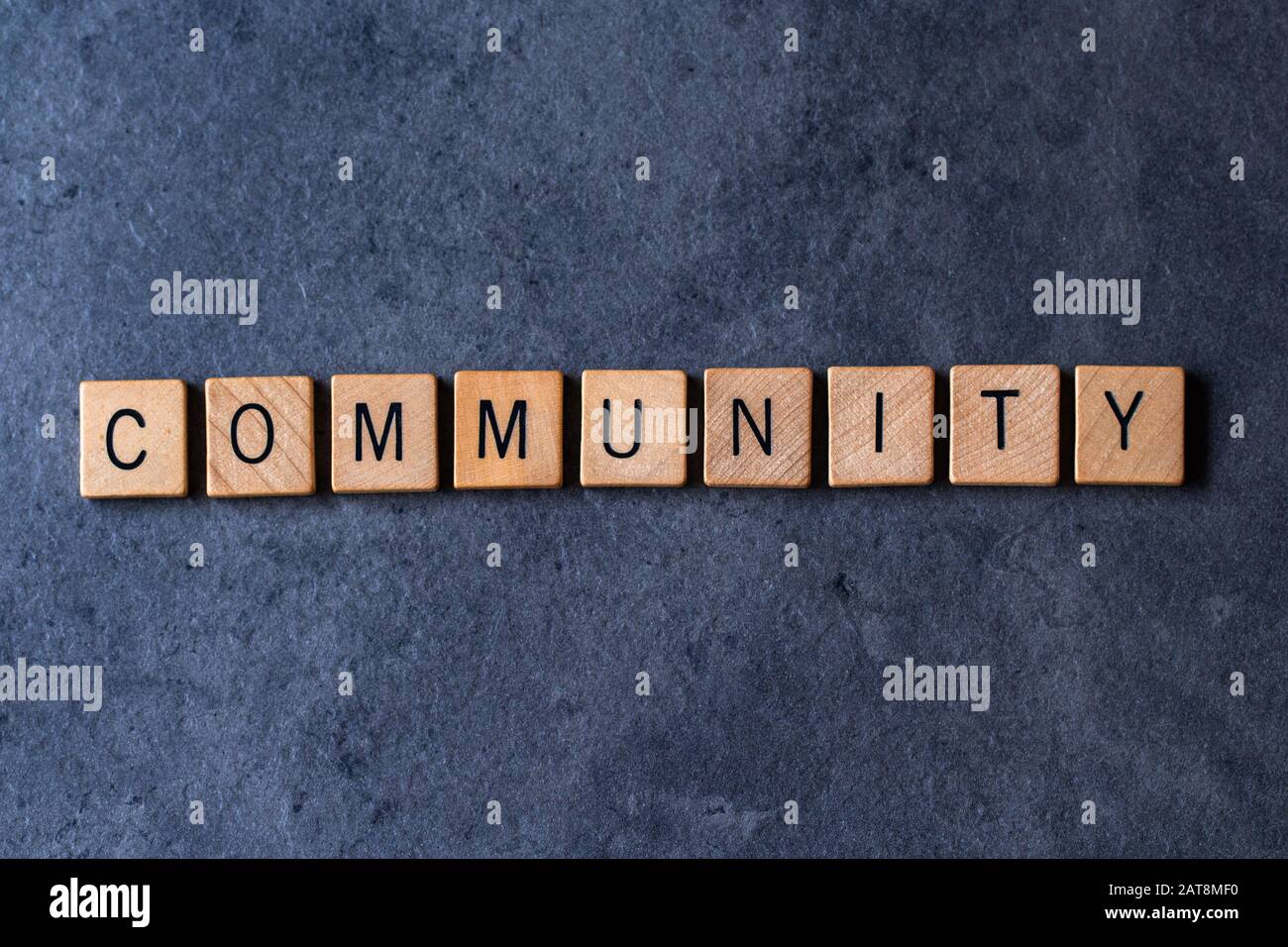 'Community' scritto in piastrelle di legno lettera su uno sfondo scuro e ruvido Foto Stock