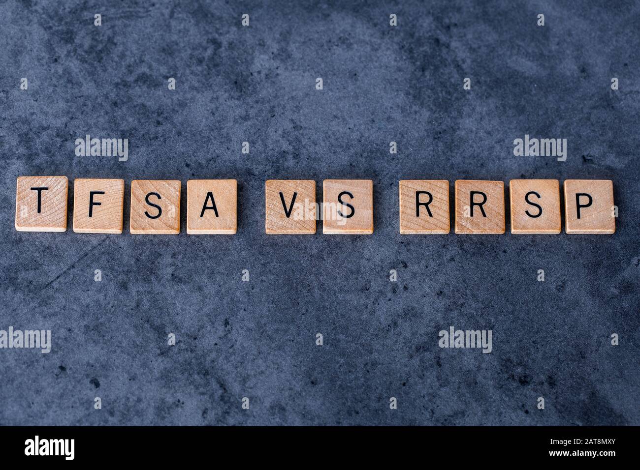 'TFSA vs RRRSP' scritto in piastrelle di legno lettera su uno sfondo scuro ruvido Foto Stock
