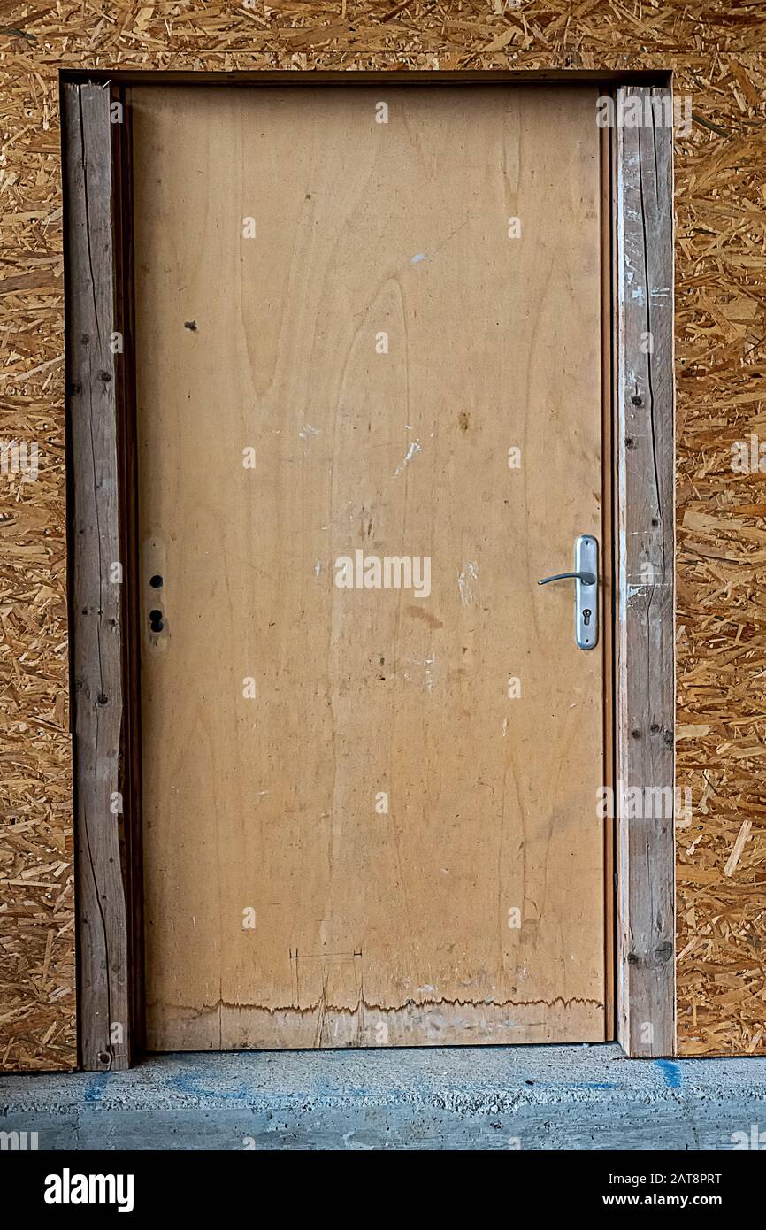 porta semplice in legno con bordi d'acqua e parete truciolare, sicurezza temporanea o salotto Foto Stock