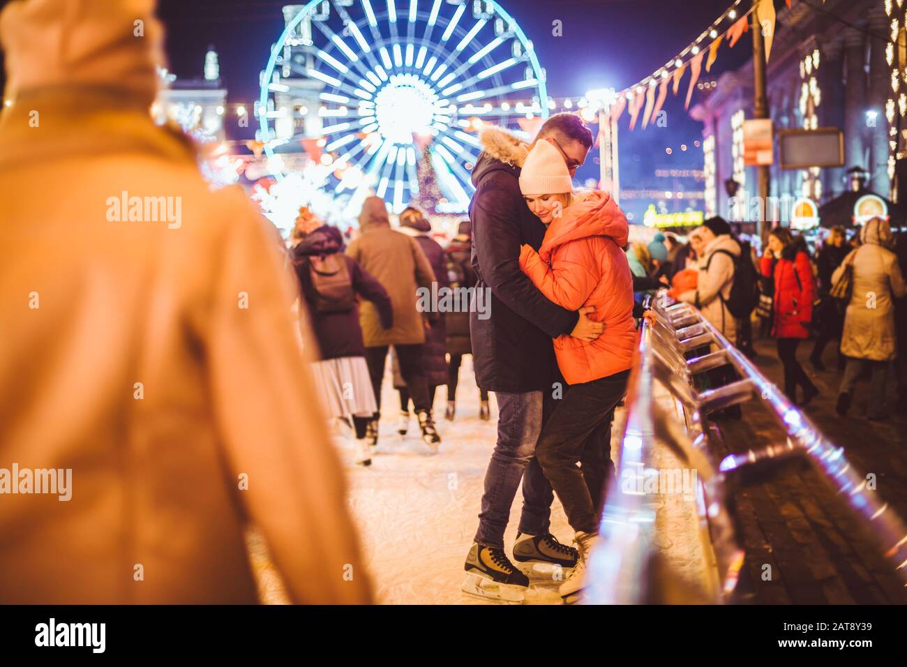 Coppia abbracciando San Valentino. Giovane coppia romantica divertirsi all'aperto in inverno. San Valentino presso la pista di pattinaggio della città. Vacanze di Capodanno Foto Stock