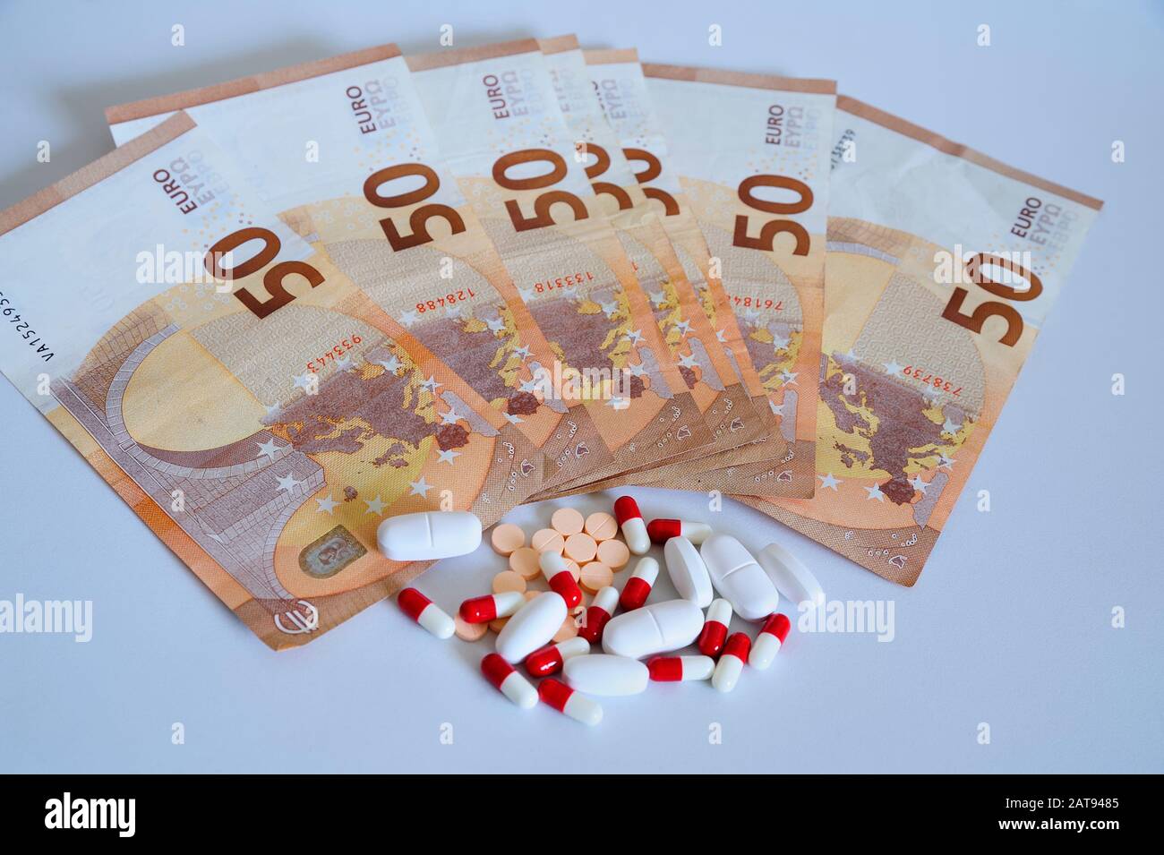 Lotto di farmaci in compresse e pillole accanto a cinquanta euro banconote sulla superficie bianca. Foto Stock