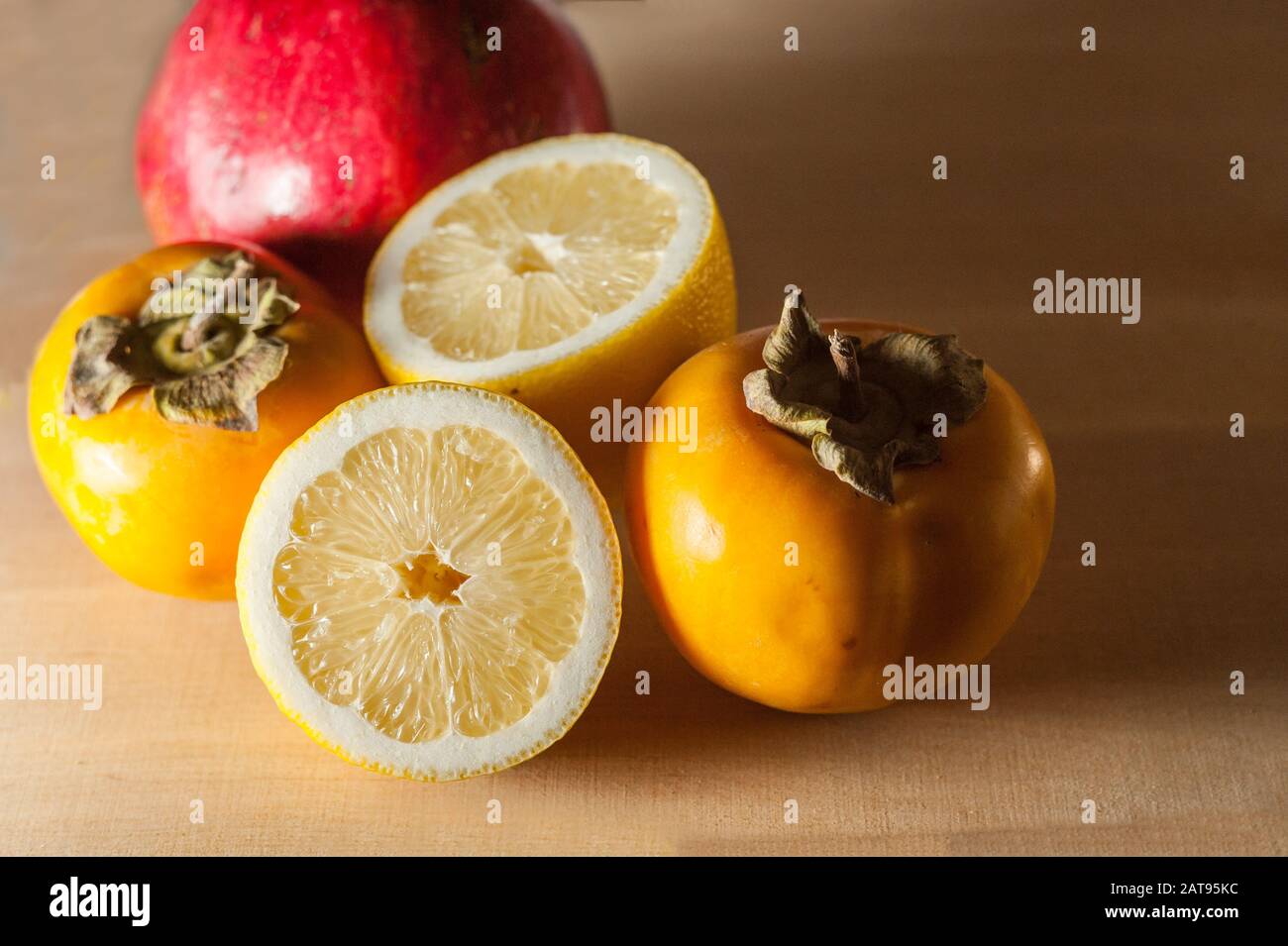 melograno, limone e persimmone su una tavola di legno Foto Stock